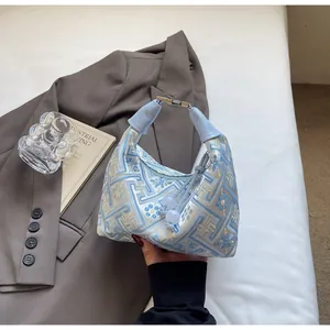 Detail view of a jacquard hobo bag with traditional patterns on a brown suit background