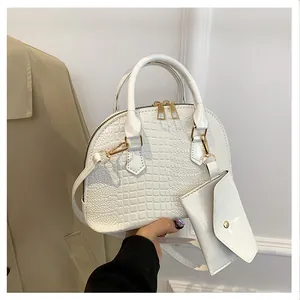 Close-up of white crocodile pattern shell bag with golden hardware and mini pouch