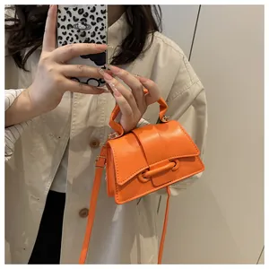 Mirror selfie showing a vibrant orange mini crossbody bag with a large circular buckle