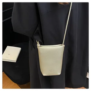 Close-up of golden lychee grain leather mini crossbody bag with embossed brand logo