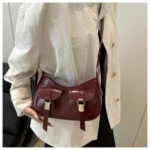 Detailed view of a vintage burgundy gloss leather shoulder bag with double buckled pockets
