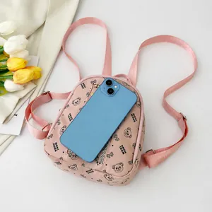 Mini sac à dos rose avec motif d'ours posé à côté d'un smartphone pour l'échelle
