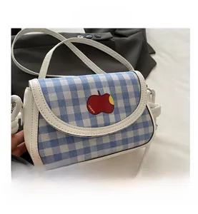 Detail of blue plaid crossbody bag with red apple embroidery and white leather trim