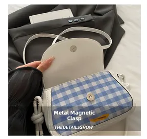 Detail showing hardware magnetic snap closure on blue and white checkered saddle bag