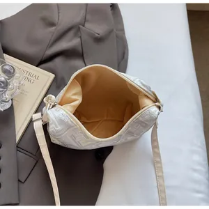 Detailed embroidery on a cream dumpling bag with zipper and yellow lining