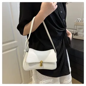 Close-up of white leather saddle bag with gold metal clasp and adjustable shoulder strap