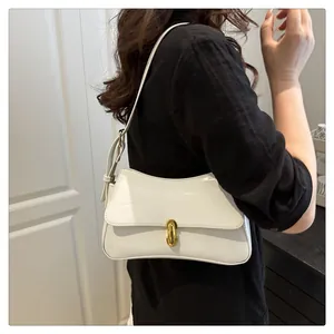 Close-up of a white patent leather saddle bag featuring a stylish gold ring metal buckle