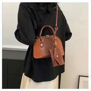 Detail of a brown crocodile pattern shell bag with a small envelope charm and gold hardware