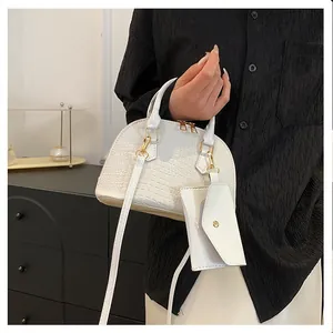 Detail of white crocodile pattern shell bag with mini purse pendant and gold hardware