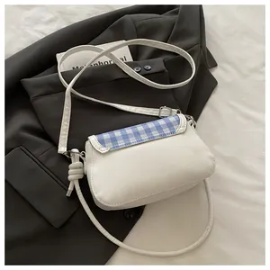 Detail shot of mini saddle bag featuring blue checkered flap and embroidered texture