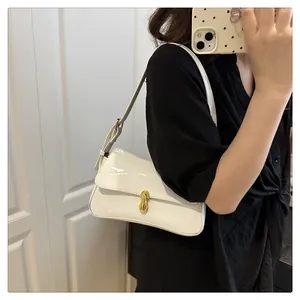 Close-up of white patent leather shoulder bag with glossy finish and gold metal buckle