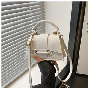 Detailed macro view of a white minimalist handbag with gold metal rings and textured flap