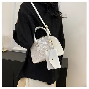 White crocodile pattern shell bag with small coin purse shown on a model's shoulder