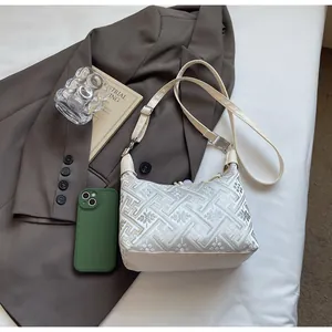 Detailed close-up of cream shoulder bag featuring silver floral embroidery and leather trim
