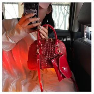 Detail of red crocodile texture shell bag with mini pouch, shown in a car interior