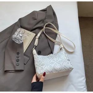 Close-up of beige hobo bag with silver embroidery and adjustable shoulder strap detail