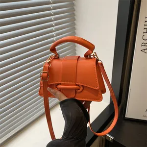 Minimalist bright orange leather handbag with top handle and gold-tone buckle