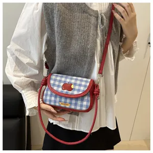 Detail of blue plaid mini crossbody bag with red apple embroidery and leather strap
