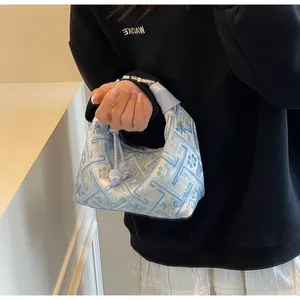 Detail view of dumpling bag with blue and white geometric patterns held by a model