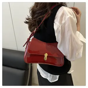 Detail of red patent leather shoulder bag with a polished golden rectangular clasp