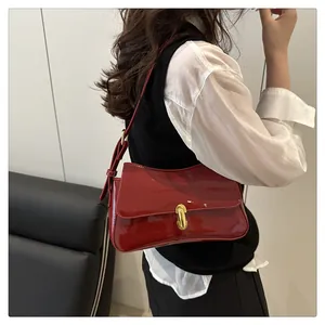 Close-up of a glossy red patent leather underarm bag with gold capsule metal buckle