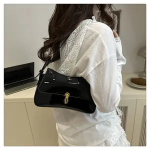 Detail of glossy black patent leather shoulder bag with golden cylindrical metal buckle