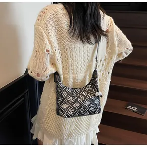 Detailed view of black and white dumpling bag with traditional pattern on a shoulder strap