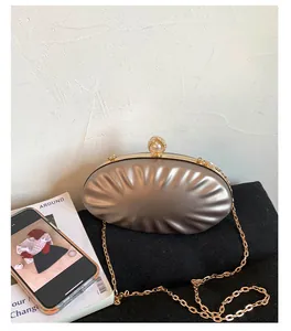 Detail of champagne shell evening clutch featuring pleated texture and pearl clasp closure
