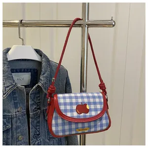 Close-up of checkered mini saddle bag with red apple embroidery and leather trim