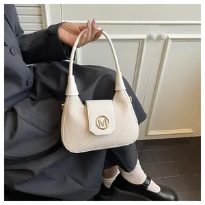 Détail du sac à main tissé crème avec boucle dorée M sur un manteau gris