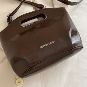 Detail of a dark brown glossy leather tote bag with Fashion & Bags text on white fabric