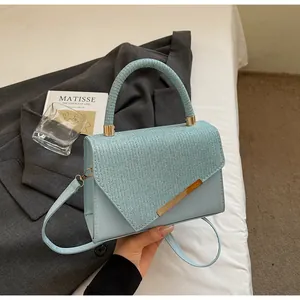 Détail du sac bandoulière bleu clair avec rabat texturé et garniture en métal doré
