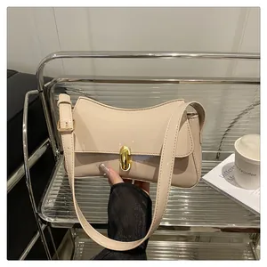 Close-up of beige glossy leather baguette bag with golden buckle and adjustable shoulder strap