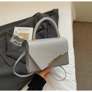 Détail du sac carré gris argenté avec rabat à paillettes et poignée ronde tressée