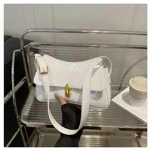 Close-up of white patent leather shoulder bag with a gold metal twist lock and strap