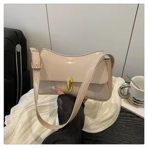 Detail of cream patent leather saddle bag featuring a polished gold twist lock closure