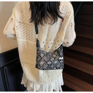 Detail of black and white geometric pattern handbag with a white sphere charm
