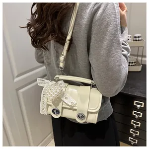 Detalle de bolso Boston blanco roto con lazo de encaje, corazón de perlas y cierres