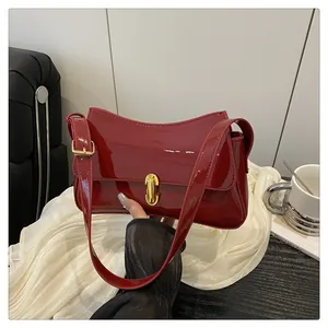 Detail of dark red patent leather armpit bag with elegant gold rectangular twist lock