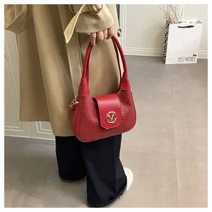 Détail du sac à main rouge tressé avec logo M doré et style trench-coat automnal chic