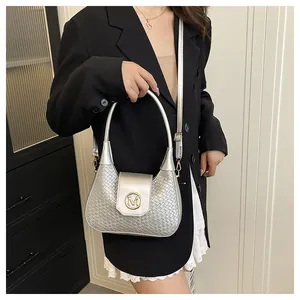 Silver woven shoulder bag with gold M buckle worn by a model in a modern suit