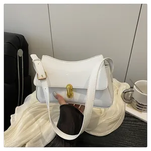 Close-up of a white patent leather baguette bag with a gold twist lock and hardware