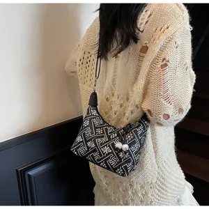 Detail of crossbody dumpling bag with geometric patterns and decorative marble beads