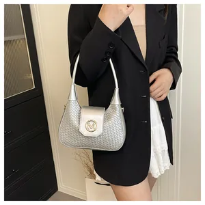 Détail du sac demi-lune argenté tressé avec logo M doré sur le rabat en cuir lisse
