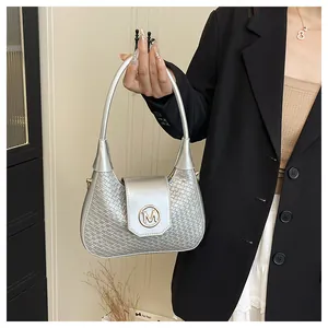 Gros plan d'un sac à main argenté tressé avec logo M doré et poignée cylindrique
