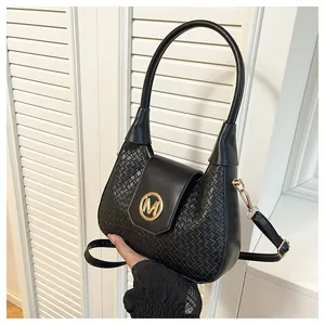 Détail du sac demi-lune tissé noir avec logo M doré et bandoulière réglable pratique