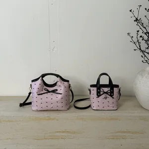 Sac seau en jacquard rose avec motifs de nœuds noirs et bandoulière en métal chic