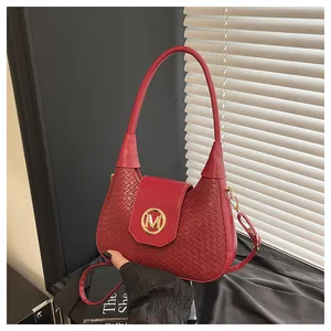Détail d'un sac hobo rouge avec texture en cuir tressé et emblème logo M en métal