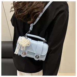 Detalle de bolso bandolera azul claro con corazón de encaje blanco y colgante de perlas