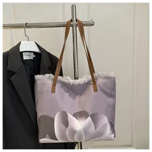 Detalle del bolso tote de lona lavanda con estampado floral, flecos y correas marrones